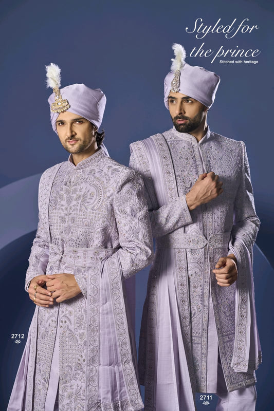 Two men in traditional embroidered suits with turbans against a blue background.