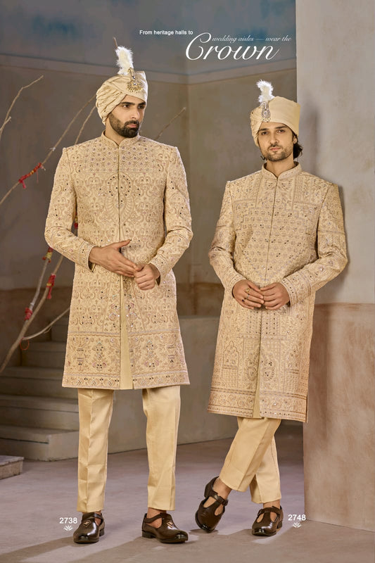 Two men in traditional embroidered sherwanis with decorative turbans indoors.