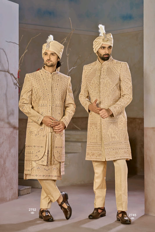 Two men in traditional beige embroidered sherwanis standing against a neutral background.