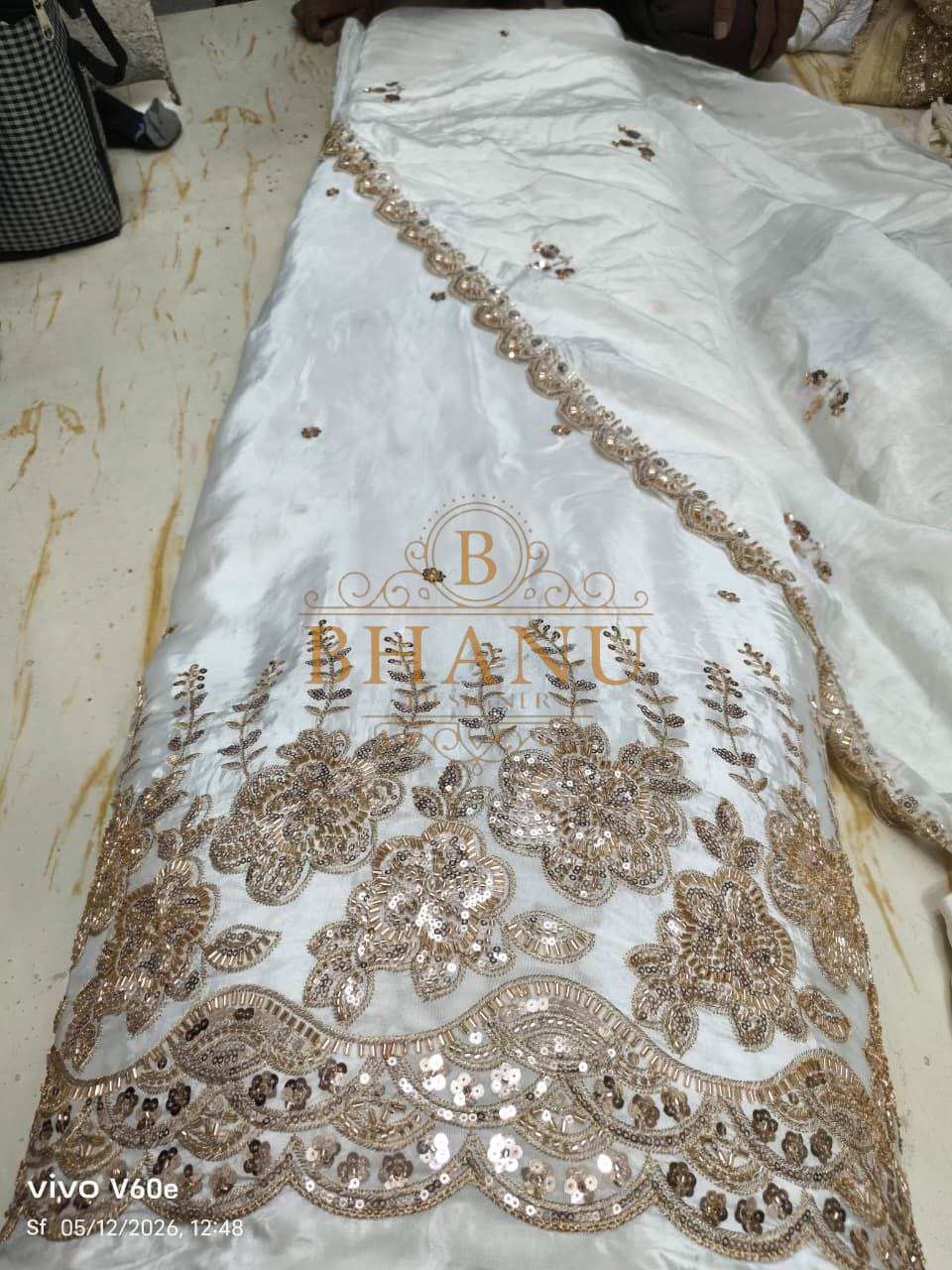 White satin with a gold sequin floral hem - fabric by the metre