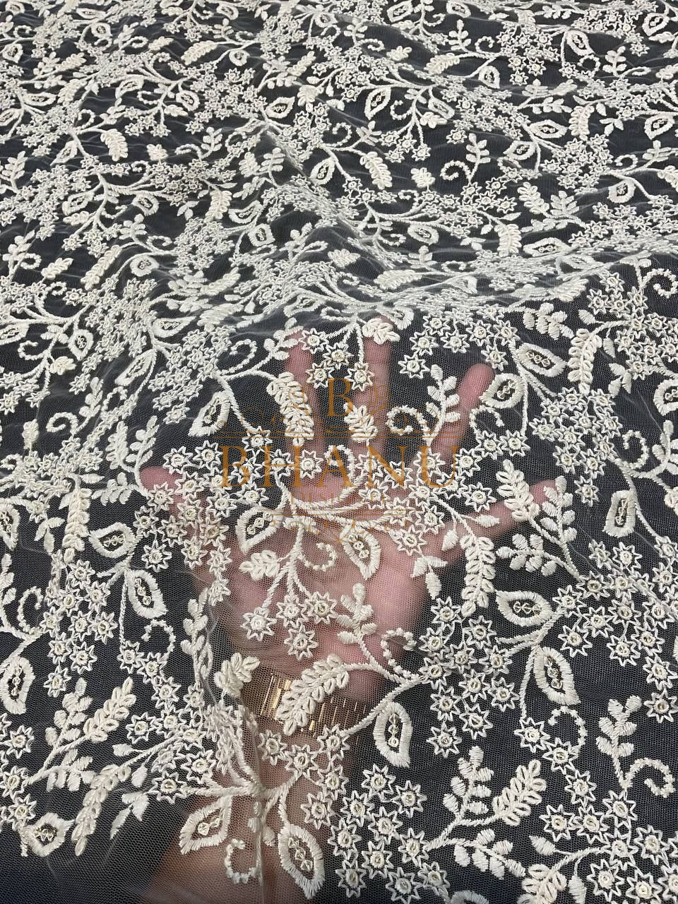 Ivory floral net over a dark ground - fabric by the metre
