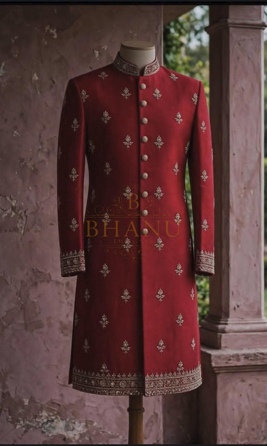 Red sherwani scattered with small gold motifs and an embroidered hem band